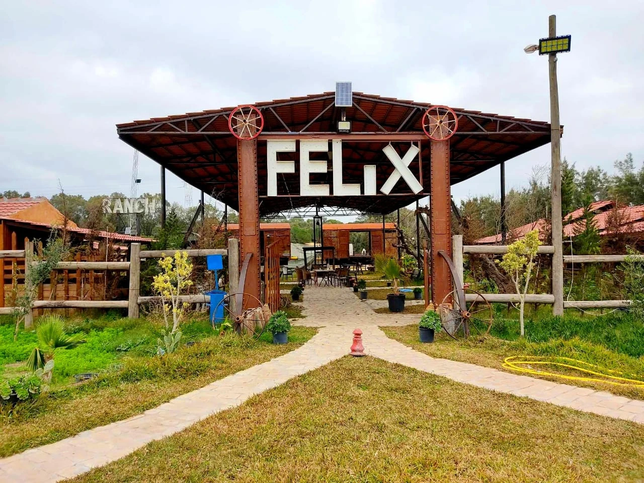 Entrée principale du Ranch Félix Haddad avec l'enseigne "FELIX" sous un auvent rustique entouré de verdure.